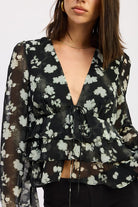 Close-up of chiffon floral top showing tie detail and layered ruffles.
