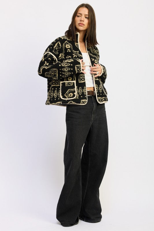 Side angle of patterned sherpa jacket layered over white top and jeans.
