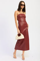 Side view of burgundy strapless textured midi dress with sleek finish, paired with silver heels and ivory bag-AVAH