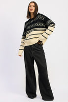 Full-body view of model wearing black and cream Fair Isle sweater with wide-leg black jeans