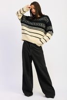 Full-body view of model wearing black and cream Fair Isle sweater with wide-leg black jeans