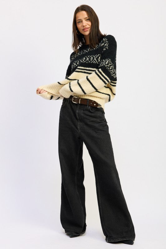 Full-body view of model wearing black and cream Fair Isle sweater with wide-leg black jeans