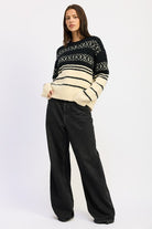 Full-body view of model wearing black and cream Fair Isle sweater with wide-leg black jeans