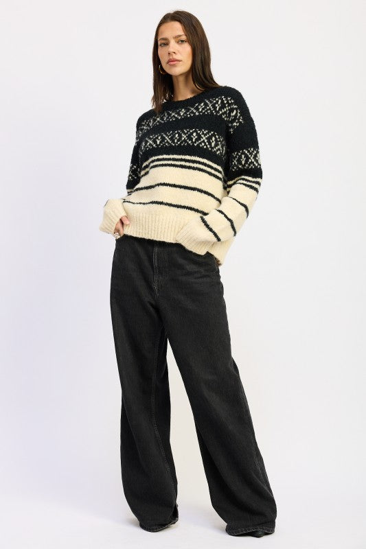 Full-body view of model wearing black and cream Fair Isle sweater with wide-leg black jeans