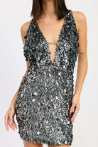 Close-up of silver textured paillette mini dress showing deep-V neckline and reflective detailing.