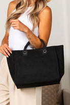 Black canvas tote with zip top closure, chain shoulder strap, and silver hardware