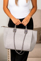 Gray canvas tote bag with silver chain shoulder strap and structured silhouette
