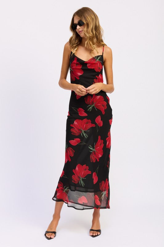Model wearing a black floral slip dress with red flowers on a white background