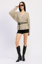 Full-length shot of warm grey belted knit sweater paired with boots and sunglasses – street-style pose