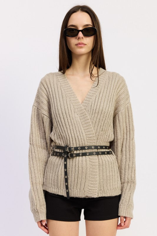 Model wearing warm grey ribbed wrap knit sweater with black grommet belt and black shorts 