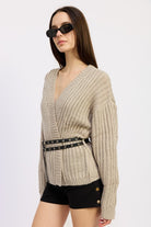 Side view of model in warm grey ribbed knit wrap sweater with double grommet belt
