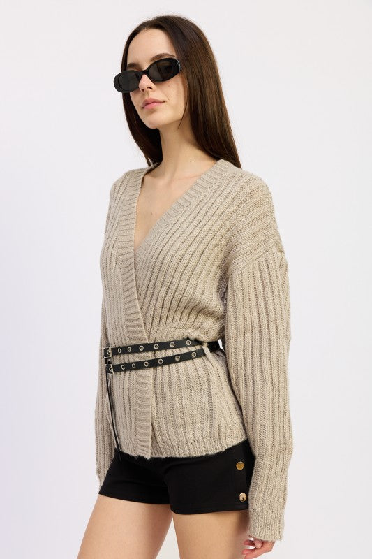 Side view of model in warm grey ribbed knit wrap sweater with double grommet belt
