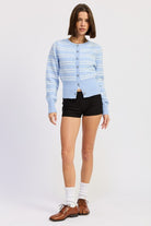 Model wearing a light sky blue striped cardigan styled with black shorts and loafers.