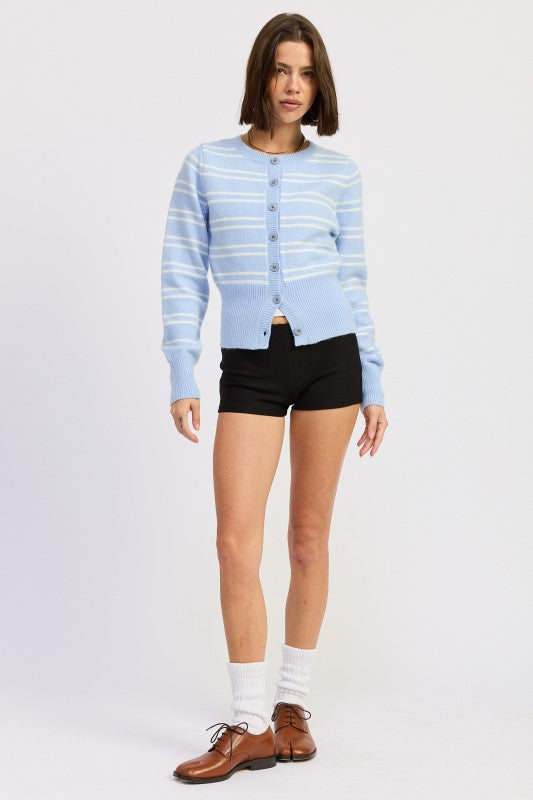 Model wearing a light sky blue striped cardigan styled with black shorts and loafers.