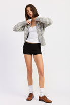 Model wearing grey and white striped button cardigan with white tank, black shorts and brown loafers