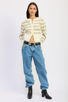 Model wearing a striped ivory and olive cardigan, blue jeans, and black boots on a white background