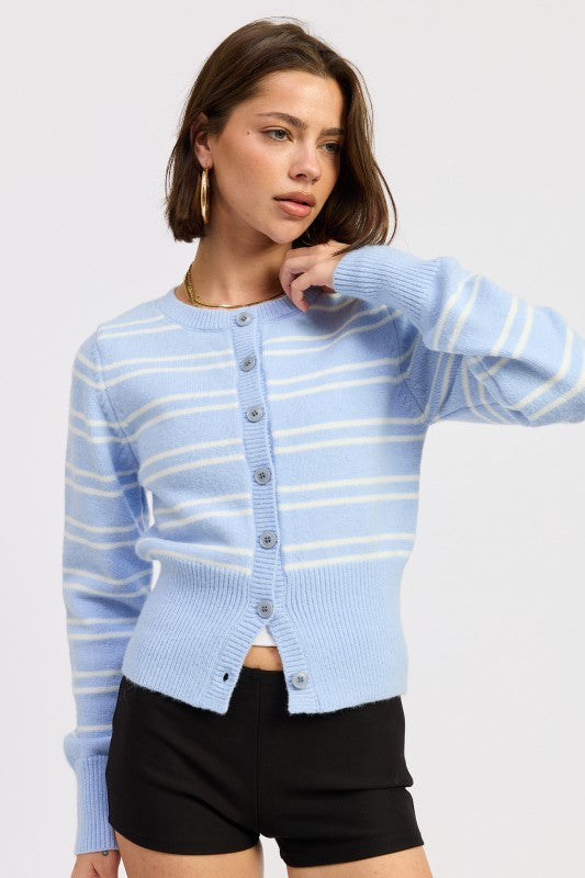 Woman wearing a light blue cardigan with white stripes on a plain background