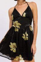 Close-up of black halter dress featuring gold floral detailing and V-neckline
