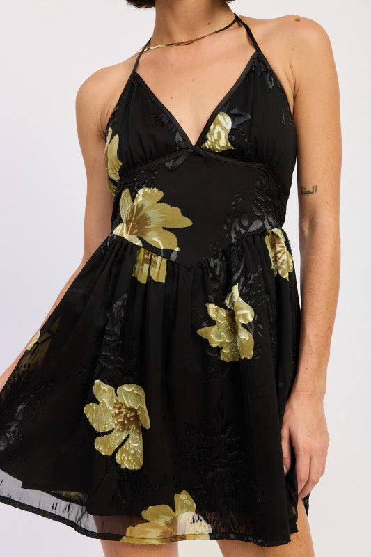 Close-up of black halter dress featuring gold floral detailing and V-neckline
