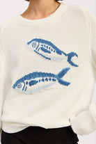 Close-up of blue fish graphic on an ivory cotton knit sweater

