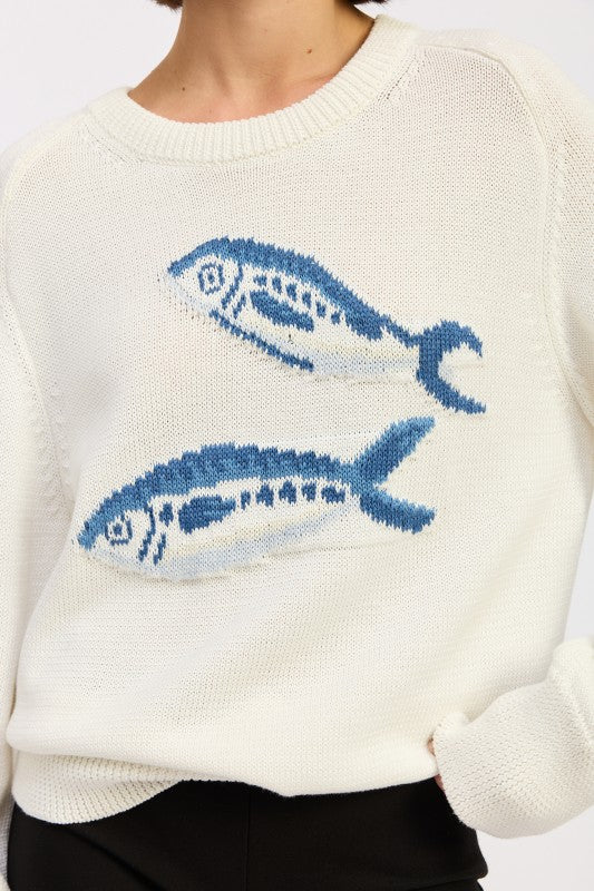 Close-up of blue fish graphic on an ivory cotton knit sweater
