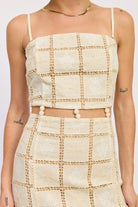 Close-up of cream crochet lattice mini dress showing embroidered pattern and beaded waist.

