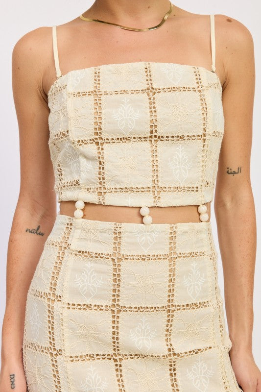 Close-up of cream crochet lattice mini dress showing embroidered pattern and beaded waist.
