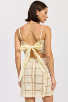 Full back view of cream crochet mini dress with oversized bow tie and open-back design.
