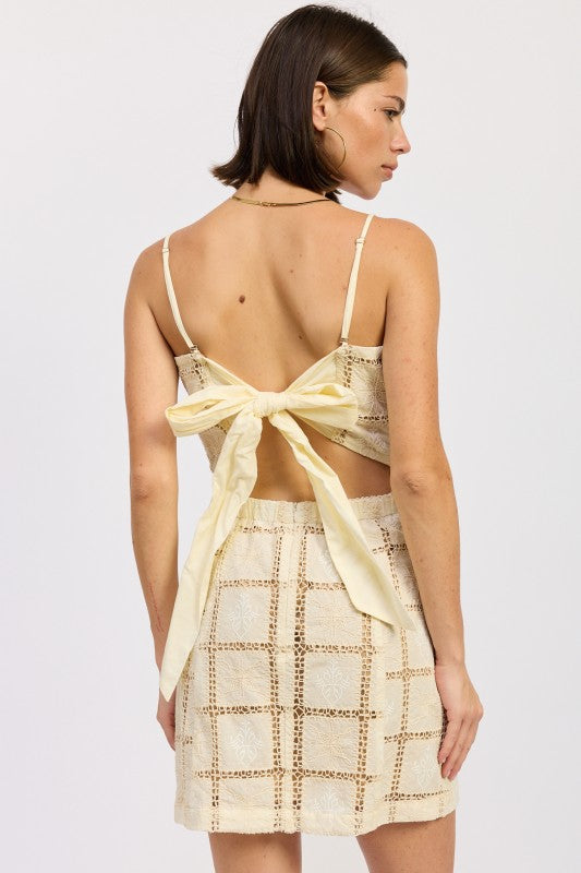 Full back view of cream crochet mini dress with oversized bow tie and open-back design.