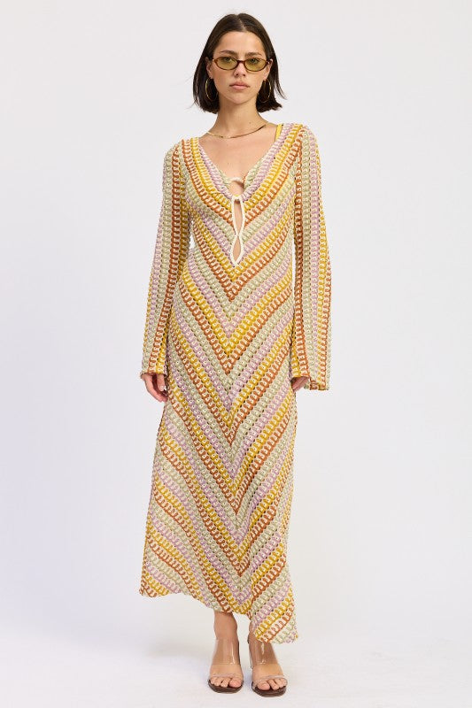 Model wearing the Sunwoven Chevron Long Sleeve Maxi Dress featuring a multicolor chevron crochet-inspired knit, deep V neckline with tie detail, and flowing maxi silhouette.