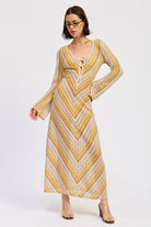 Model wearing the Sunwoven Chevron Long Sleeve Maxi Dress featuring a multicolor chevron crochet-inspired knit, deep V neckline with tie detail, and flowing maxi silhouette.