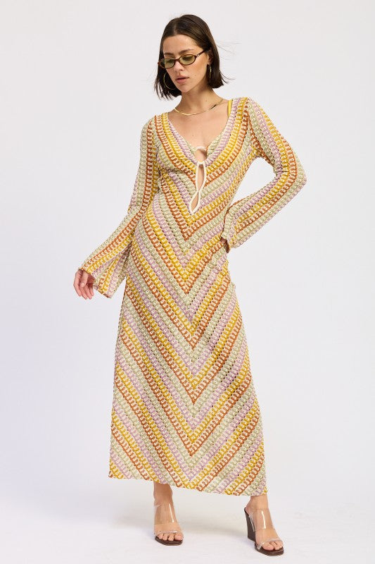 Model wearing the Sunwoven Chevron Long Sleeve Maxi Dress featuring a multicolor chevron crochet-inspired knit, deep V neckline with tie detail, and flowing maxi silhouette.