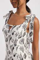 Close-up of seashell print dress showing tie straps and bead-accented neckline.