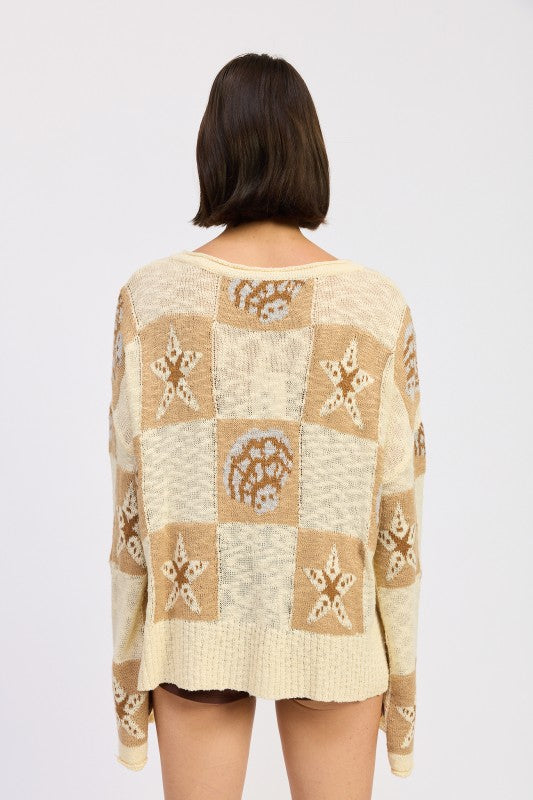 Back view of cream and taupe patchwork sweater with star and seashell design.
