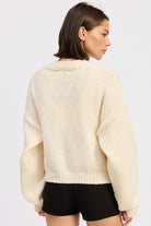 Back view of ivory cardigan showing clean knit texture without embroidery.