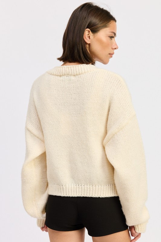 Back view of ivory cardigan showing clean knit texture without embroidery.