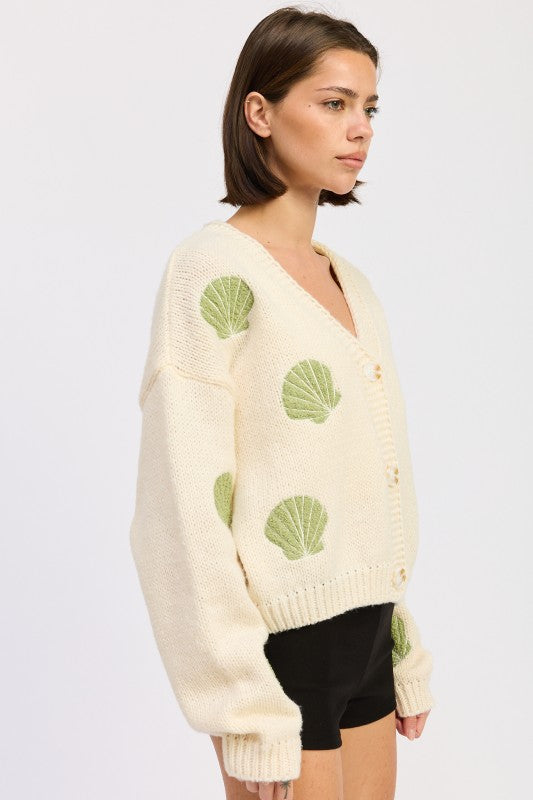 Side view of ivory seashell cardigan highlighting oversized sleeves and textured knit.

