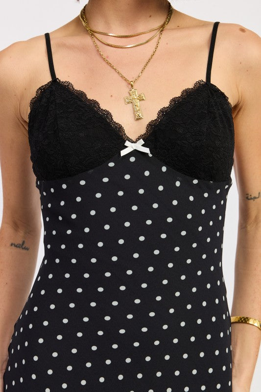 Close-up of black lace bust and bow detail on black polka dot slip dress.
