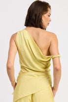 Woman wearing a pale yellow one shoulder asymmetrical top with black stripe against a white background