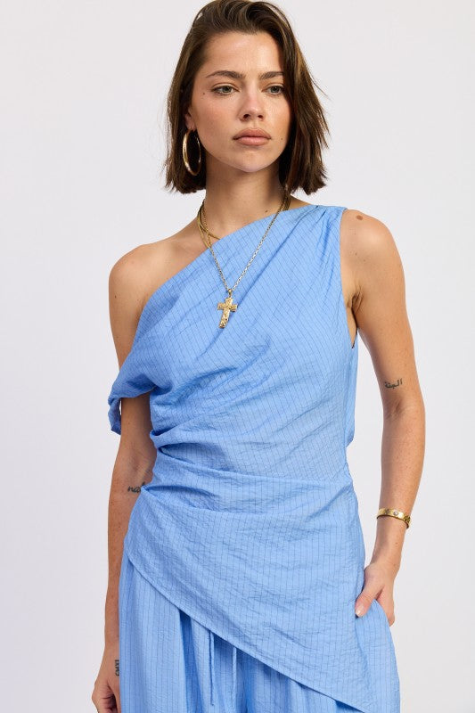 Woman wearing a blue one shoulder asymmetrical top with black stripe against a white background
