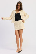 Ivory Reverie Textured Cropped Jacket in cream, styled with mini skirt and black heels for a coordinated look.