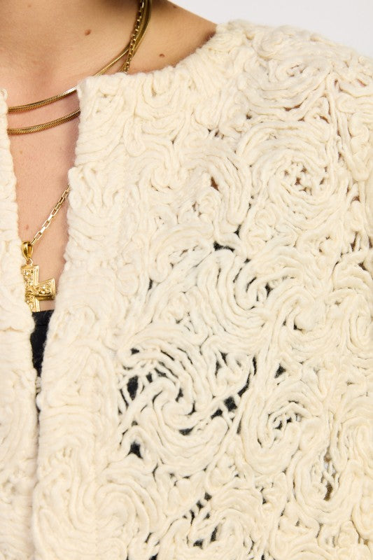 Close-up of Ivory Reverie Textured Cropped Jacket showing swirl knit pattern and soft cream fabric.