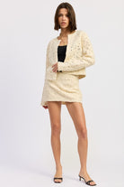 Front view of Ivory Reverie Textured Mini Skirt in cream, styled with matching jacket and black top.