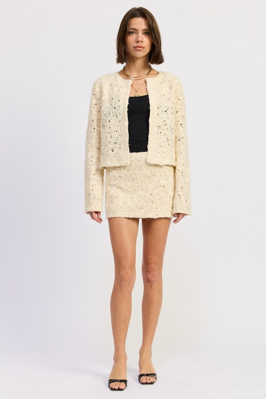 Front view of Ivory Reverie Textured Mini Skirt in cream, styled with matching jacket and black top-AVAH