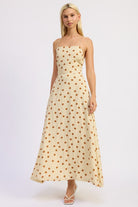 Model wearing a butter cream maxi dress with caramel polka dots and a straight neckline.