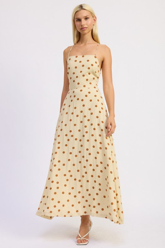 Model wearing a butter cream maxi dress with caramel polka dots and a straight neckline.