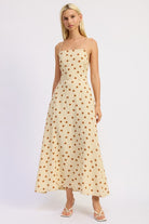 Model wearing a butter cream maxi dress with caramel polka dots and a straight neckline.