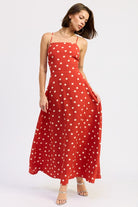 Model wearing a red polka dot maxi dress with a straight neckline and thin straps.