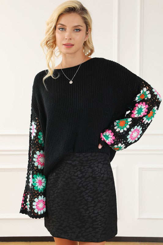 Black knit sweater with colorful crochet floral sleeves, front view