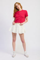 Fuchsia cropped cardigan styled with white mini skirt, full body view
